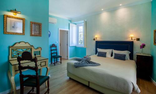 een slaapkamer met blauwe muren en een bed en een bureau bij Palácio de Sintra Boutique House in Sintra