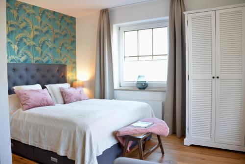 Un dormitorio con una cama con almohadas rosas y una ventana en HAPPY PLACE mit Sonnen-Balkon und Stellplatz nur 400 m zum Strand, en Scharbeutz