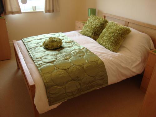 a large bed with green and white sheets and pillows at Riverbank Penthouse and Apartments in Cardiff