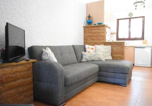 uma sala de estar com um sofá cinzento e uma televisão em Sani Garden House em Sani Beach