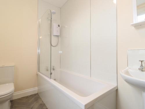 a white bathroom with a shower and a toilet at Pond Cottage in Alnwick