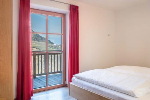 ein Schlafzimmer mit einem Bett und einem großen Fenster in der Unterkunft Apartments Gojer Vernatsch in Karneid