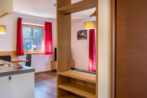 eine Küche mit roten Vorhängen und einem Spiegel in der Unterkunft Apartments Gojer Vernatsch in Karneid