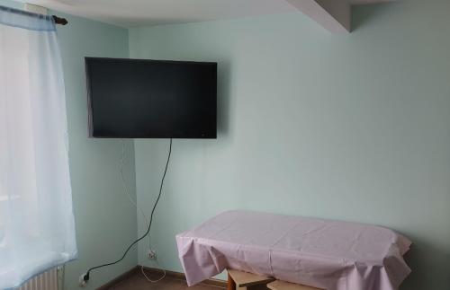 a flat screen tv hanging on a wall with a table at Hostel u Misiów in Suwałki