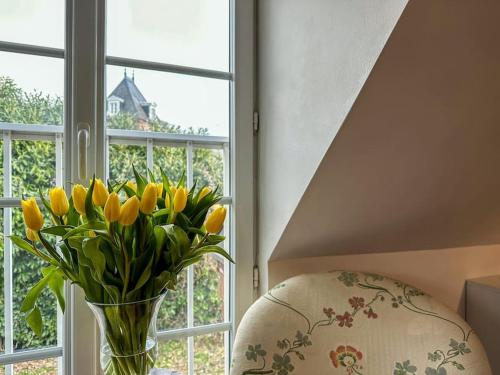 a vase of yellow flowers sitting next to a window at L'Indépendance - Cottage - Château Le Bas Bleu in Quesnoy-le-Montant