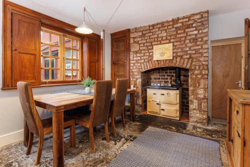 a dining room with a table and a brick fireplace at Air Host and Stay - Anfield cottage, 2 bedroom 2 bathroom in Liverpool
