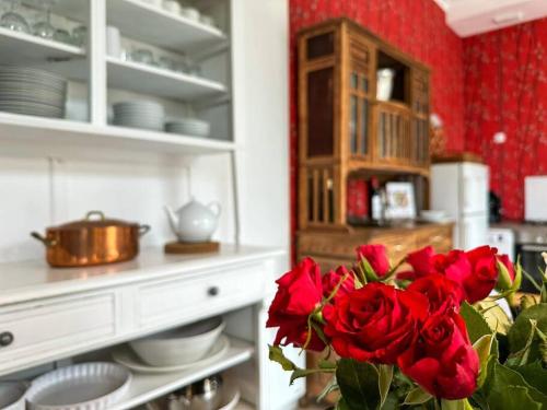 a vase of red roses in a kitchen at L'Indépendance - Cottage - Château Le Bas Bleu in Quesnoy-le-Montant