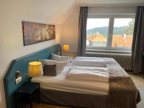 a bedroom with a bed with a large window at Berghotel HARZ in Hahnenklee-Bockswiese