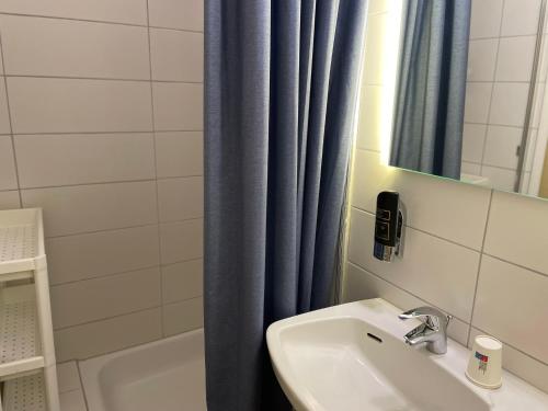 a bathroom with a sink and a blue shower curtain at Berghotel HARZ in Hahnenklee-Bockswiese