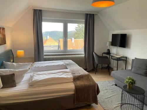 a bedroom with a bed and a window and a couch at Berghotel HARZ in Hahnenklee-Bockswiese