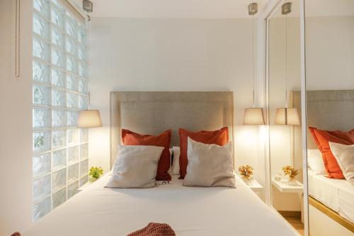 um quarto com uma cama com almofadas laranja e branca em Apartamentos Martalia Marbella Banús em Marbella