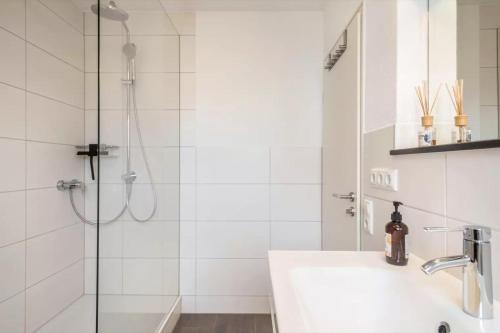 La salle de bains blanche est pourvue d'une douche et d'un lavabo. dans l'établissement Fewo Hotz am Golfclub Lindau 2b, à Lindau