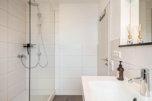 ein weißes Bad mit einer Dusche und einem Waschbecken in der Unterkunft Fewo Hotz am Golfclub Lindau 2a in Lindau