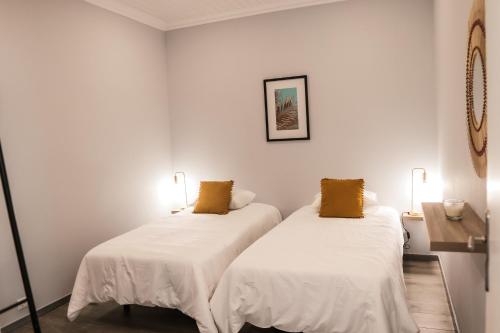 two beds in a room with white walls at Casa Maresia in Fenais da Luz