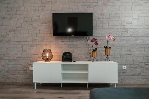 a white cabinet with a tv on a brick wall at Casa Maresia in Fenais da Luz