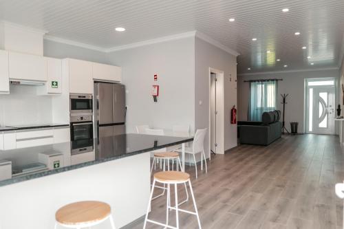 una cocina con armarios blancos y taburetes de bar en Casa Maresia, en Fenais da Luz