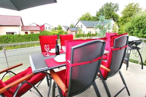 ゲーレン・レビンにあるVILLA HUeGEL _ OG_Fewoのパティオテーブル(赤い椅子付)、ワイングラス