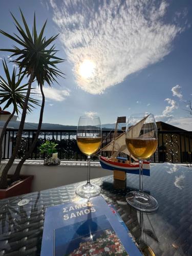 two glasses of wine sitting on a table on a balcony at Aegean Blue House - Spectacular Seaview in Kalámion