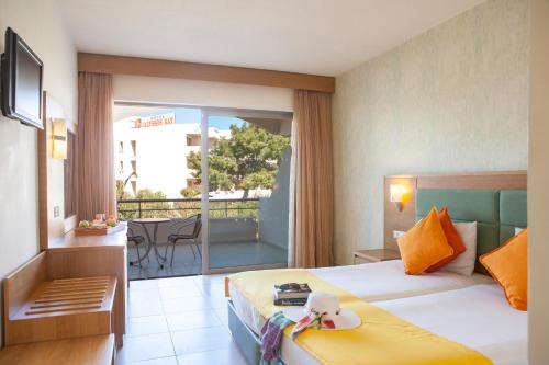 a hotel room with a bed and a balcony at IALYSSOS BAY HOTEL in Ialyssos