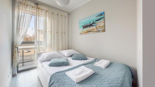 a bedroom with a bed with two pillows and a window at Apartamenty Sun & Snow Garden Gates in Gdańsk