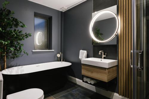 een badkamer met een bad, een wastafel en een spiegel bij The Barn at Corrstown Village in Portrush