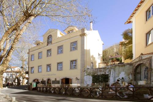 a large white building with people sitting in front of it at Casa do Vinho Sintra Guest House in Sintra
