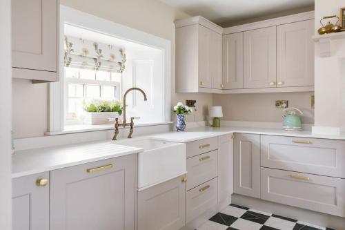 a white kitchen with white cabinets and a window at The Farmhouse at Corrstown Village in Portrush