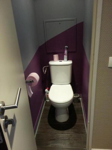 La salle de bains est pourvue de toilettes blanches dans un mur violet. dans l'établissement Paris 15 Expo Versailles Park Free, à Issy-les-Moulineaux