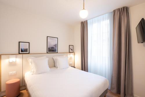 a bedroom with a large white bed and a window at Apparthotel Privilodges Le Royal in Annecy