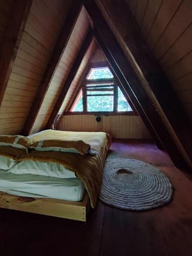 a bed in a room with a window in a tent at Alpinas de Sollipulli refugio llaima in Melipeuco
