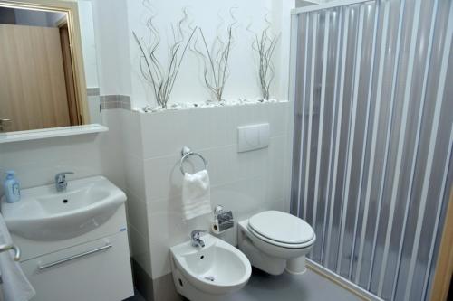 Baño blanco con aseo y lavamanos en B&B Colori del Salento, en Presicce