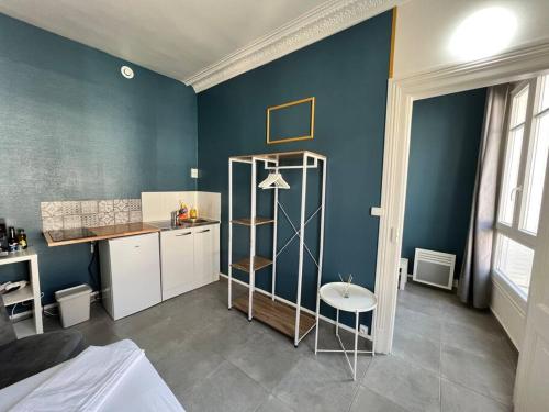 Zimmer mit einer blauen Wand, einer Küche und einem Tisch in der Unterkunft Key-s Meaux/Suite 5 Saphir/centre/Disney in Meaux