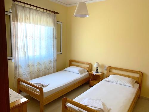 two twin beds in a room with a window at Spiros Apartments - Agios Gordios Beach, Corfu, Greece in Agios Gordios