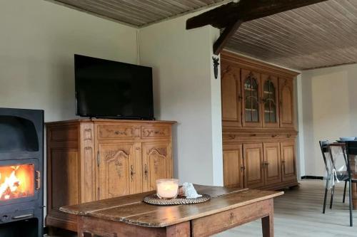 sala de estar con TV y mesa con chimenea en L'Hirondeau de Tenneville, en Tenneville