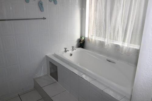 La salle de bains blanche est pourvue d'une baignoire et d'une fenêtre. dans l'établissement Laguna La Crete 47, à Margate