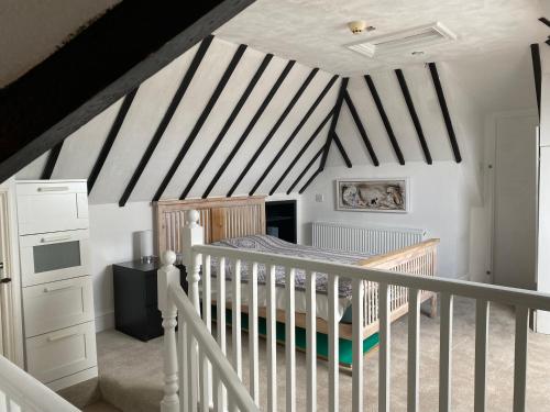 a bedroom with a crib and black and white striped ceiling at Pound Corner in Godalming