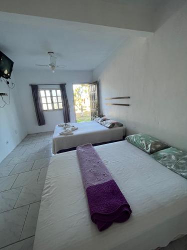 two beds in a room with two windows at Pousada Vale Do Aijalom in Cabo Frio