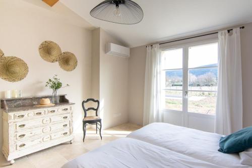 een slaapkamer met een bed, een dressoir en een raam bij Bastide la Melonnerie in Lacoste
