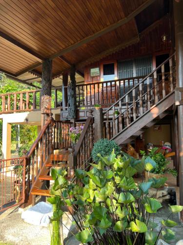 uma casa com uma escada de madeira com plantas em frente em Traditional Thai house บ้านเรือนไทย ใกล้หาดระยอง em Ban Chak Phai