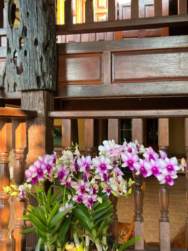 um ramo de flores em vasos ao lado de um banco em Traditional Thai house บ้านเรือนไทย ใกล้หาดระยอง em Ban Chak Phai
