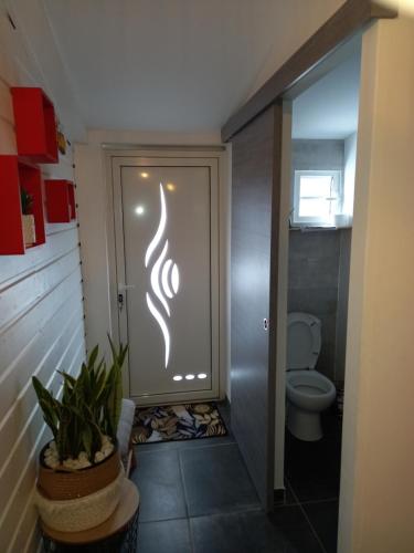 un bagno con servizi igienici e una porta con un cartello di la caz à David a Trois Bassins