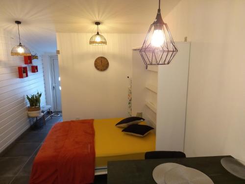 een slaapkamer met een geel bed en 2 hanglampen bij la caz à David in Trois Bassins