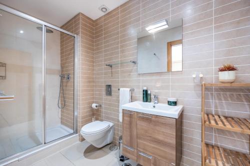 a bathroom with a toilet and a shower and a sink at Burgau Beach House in Burgau