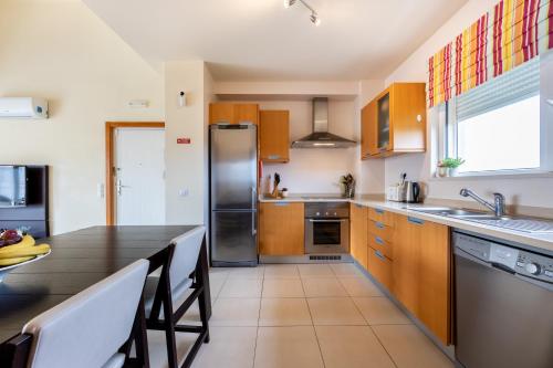 a kitchen with wooden cabinets and a table with chairs at Burgau Beach House in Burgau