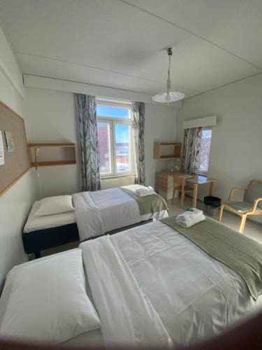 um quarto com 2 camas, uma mesa e cadeiras em EC-Hostel em Vaasa