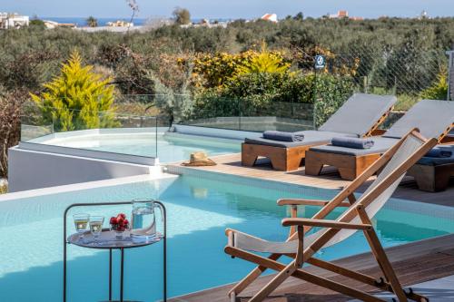 a chair and a table next to a swimming pool at Alba Bianca Villa, a Secluded Retreat, By ThinkVilla in Hersonissos
