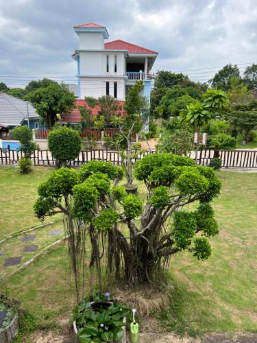 a house with a tree in front of a yard at Traditional Thai house บ้านเรือนไทย ใกล้หาดระยอง in Ban Chak Phai