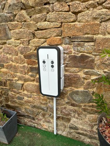 a white electric box on the side of a stone wall at Hôtel des Rochers in Perros-Guirec