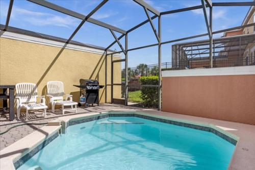 a swimming pool with two chairs and a grill at 3 Bedrooms 25 Bathrooms Encantada 3091 Yl in Orlando