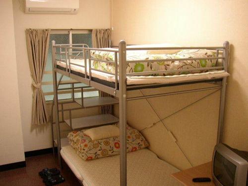 two bunk beds in a small room with a television at Grace Naha in Naha